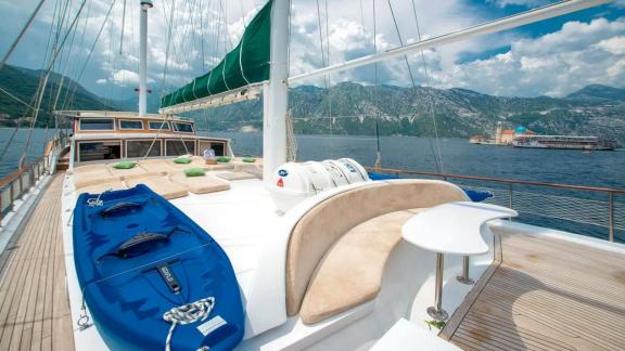 Spacious deck of a Gulet yacht with kayak and stunning mountain scenery. Relaxation and adventure combined.