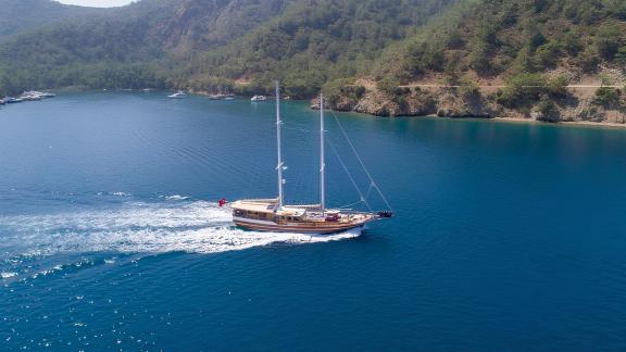 A beautiful gulet in Bodrum with 6 cabins that sails through a quiet bay with wooded slopes.