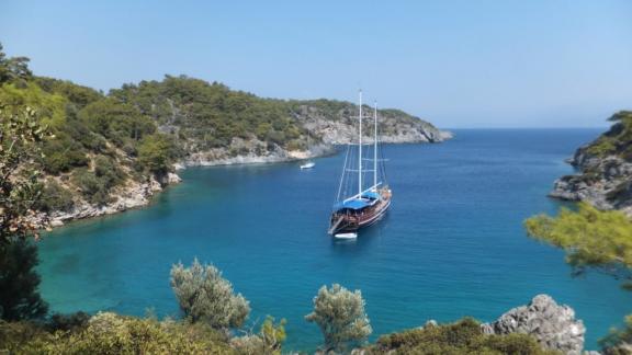 Die Gulet Semercioglu liegt vor Anker in einer malerischen Bucht mit klarem, türkisfarbenem Wasser, umgeben von grünen H