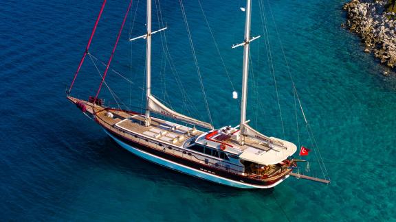 In Göcek gulet charter option Serenity 86 aerial view in turquoise water with spacious deck and sunbathing area visible.