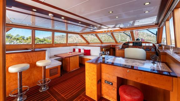 In Göcek gulet charter option Serenity 86 salon with seating area helm station and panoramic sea view visible.