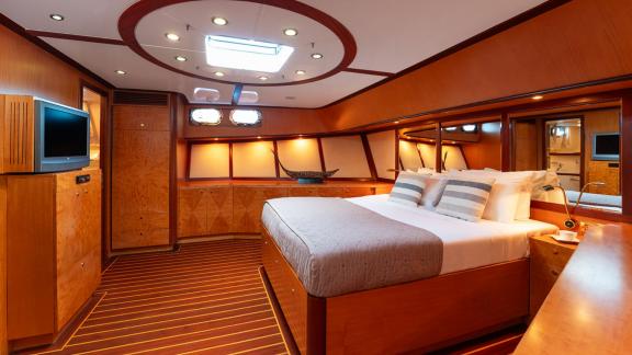 In Göcek gulet charter option Serenity 86 master cabin with large bed tv unit and spacious interior visible.