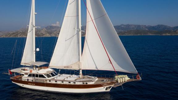 In Göcek gulet charter option Serenity 86 sailing with open sails on the sea with spacious deck and comfort visible.