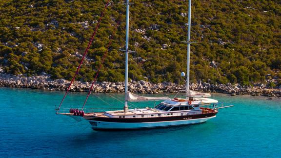 In Göcek gulet charter option Serenity 86 side view in calm bay with spacious deck and clear turquoise water visible.