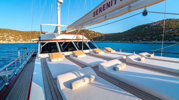 In Göcek gulet charter option Serenity 86 foredeck with sunbeds and open sea view offering relaxing space visible.