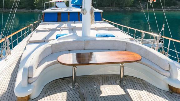 The seating area on the foredeck of Gulet Seven 1 is equipped with comfortable cushions and a wooden table.