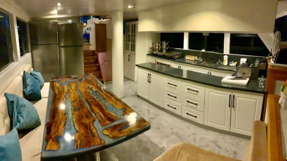 Stylish kitchen area on Gulet Simi featuring a custom wooden dining table and stainless steel appliances, perfect for co