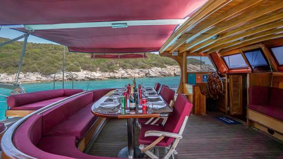 Inviting dining area with red cushions and sea view. Perfect for relaxed meals onboard.