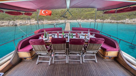 Stylish dining area on the gulet with red sunshade and sea view. Perfect setting for onboard meals.