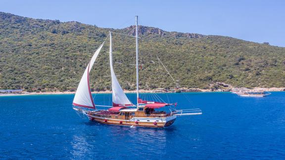 Elegant gulet with white sails off the coast of Bodrum. Perfect choice for a relaxing yacht charter.