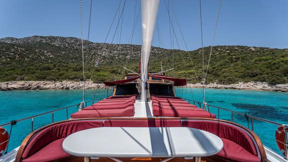 Comfortable sun deck with red loungers and table, against the stunning Bodrum coastline. Perfect for relaxing.