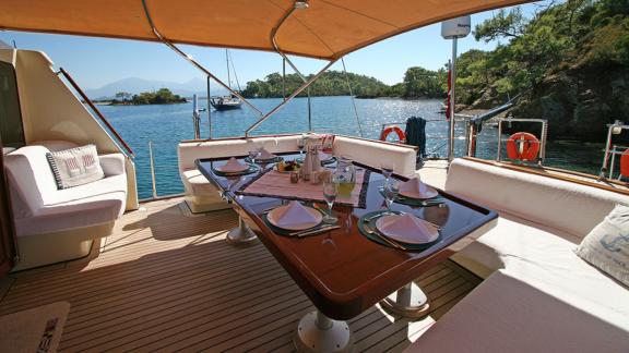 In Bodrum Gulet chartern Option Tango Charlie Achterdeck mit Esstisch und Sitzbereich mit Meerblick sichtbar.