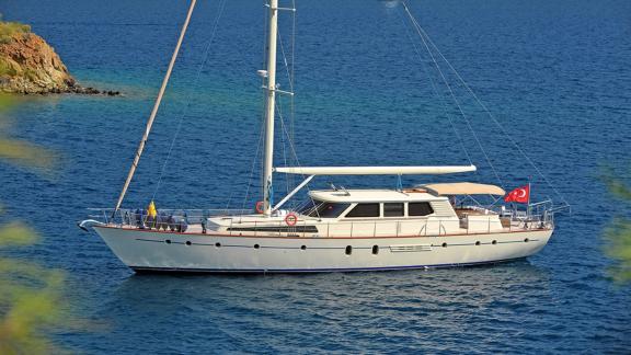 In Bodrum Gulet chartern Option Tango Charlie liegt im Meer in Seitenansicht mit Flagge sichtbar.