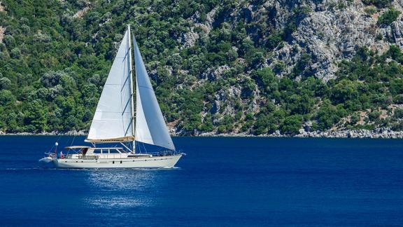 In Bodrum gulet charter option Tango Charlie sailing near the coast with open sails visible.