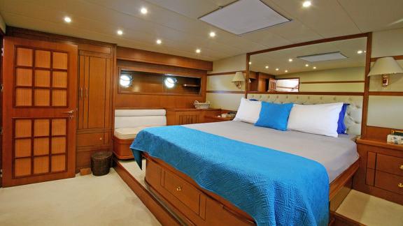 In Bodrum Gulet chartern Option Tango Charlie Masterkabine mit großem Bett Sitzbereich und Stauraum sichtbar.