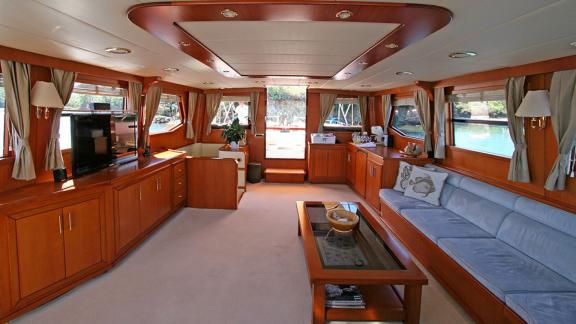 In Bodrum gulet charter option Tango Charlie interior salon with large seating and panoramic windows visible.