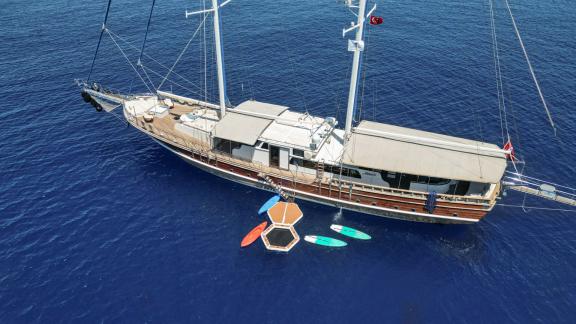 The gulet Tarkan 5 is anchored in Fethiye, surrounded by deep blue water, with paddleboards and a floating platform.