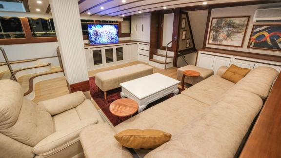 The elegant living area of the Gulet Tarkan 5, with a large sofa, armchairs, a flat-screen TV and stylish wooden accents