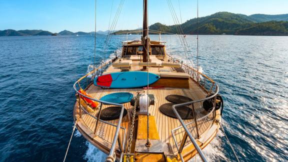 View from the stern of Gulet Thalasa towards open sea, with paddleboards and seating areas on deck.