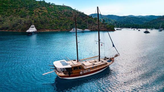 Die Gulet Thalasa segelt durch eine friedliche türkische Bucht, umgeben von bewaldeten Hügeln.