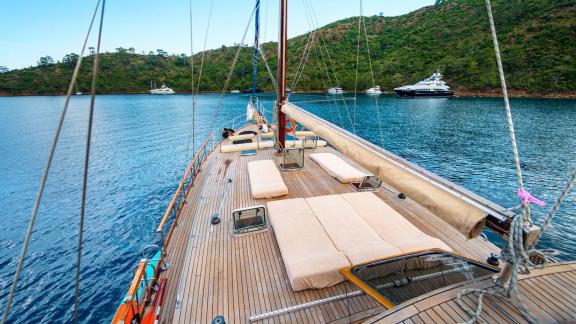 Blick über das Deck der Gulet Thalasa mit Sonnenliegen und Segel auf ruhigem Wasser.