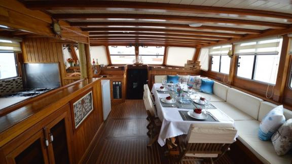 Cozy salon on Gulet Tufan 5 with a stylish dining area and view of the kitchen.