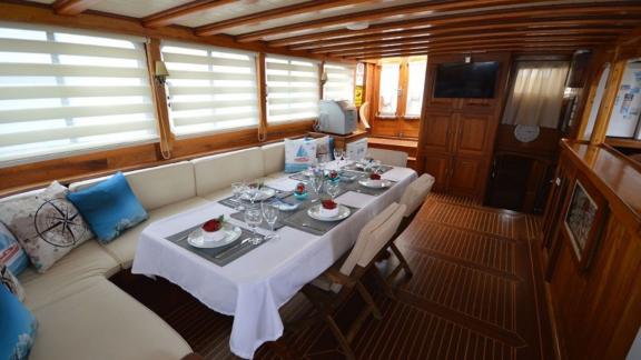 The salon of Gulet Tufan 5 with a set dining table and comfortable seating.