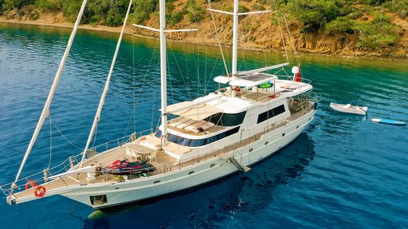 The gulet Vega is anchored in a calm, blue bay. A dinghy floats alongside the yacht.