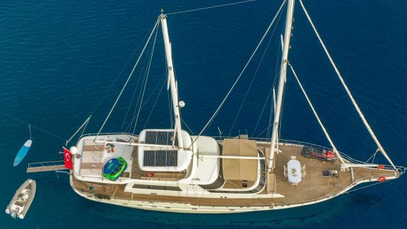 Die Gulet Vega liegt ruhig vor Anker in tiefblauem Wasser. Ein Beiboot ist neben der Yacht zu sehen.