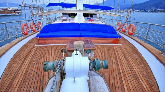 Weitläufiges Deck einer luxuriösen Gulet mit bequemen blauen Sitzmöglichkeiten und Aussicht auf das Meer.