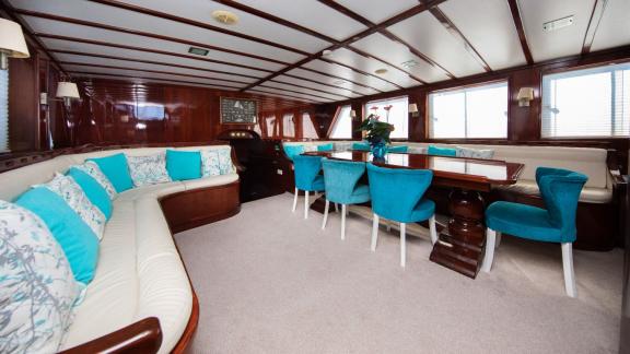 Elegant interior of the Gulet Vivere with comfortable seating and a dining table, decorated in white and turquoise.