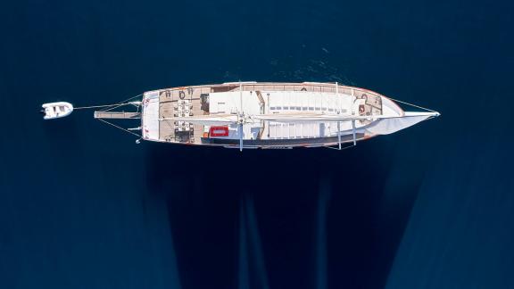 White Pearl gulet is captured from above while sailing off Athens, showing her wide deck and tender.
