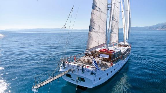 The stern view of White Pearl gulet sailing off Athens shows her open sails and swim platform.