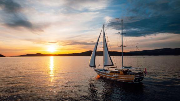 Die hölzerne Gulet Andeo fährt bei goldenen Sonnenuntergangsfarben vor der Küste von Split.