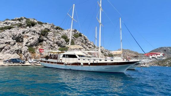 Die Gulet Zehra Sultan liegt in einer malerischen Bucht vor Anker, umgeben von felsigen Hügeln und klarem Wasser.