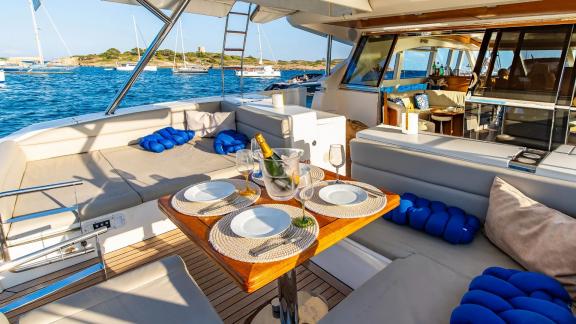 The aft deck of Parodia II in Mallorca includes a set dining table and sea-facing lounge.