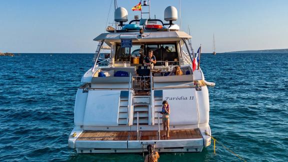 Parodia II motor yacht is anchored off Mallorca with guests on the swim platform.