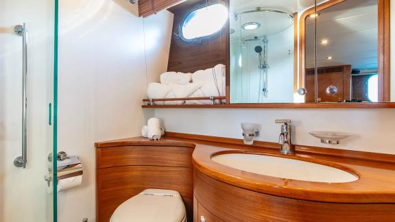 The bathroom of Parodia II in Mallorca includes a glass shower wooden counter mirror and round window.
