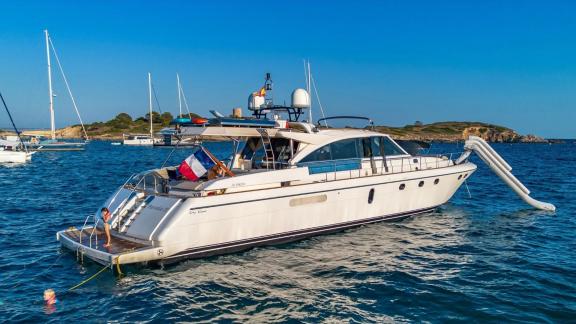 Parodia motor yacht is anchored in a cove in Mallorca with a slide and swim platform.