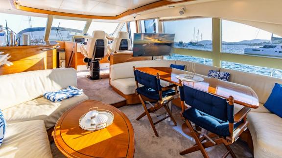 The salon of Parodia II in Mallorca features a dining table seating area TV and helm chairs forward.