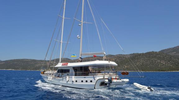 Der Gül Sultan Gulet fährt durch das blaue Wasser von Bodrum, mit grünen Bergen im Hintergrund.