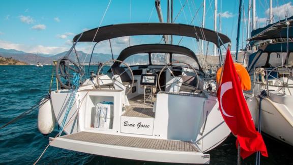 The aft deck of the Beau Gosse sailing yacht docked in the marina with the Turkish flag waving.