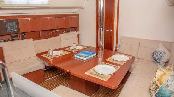 The saloon of the Beau Gosse sailing yacht features a dining table for four with a comfortable seating area.