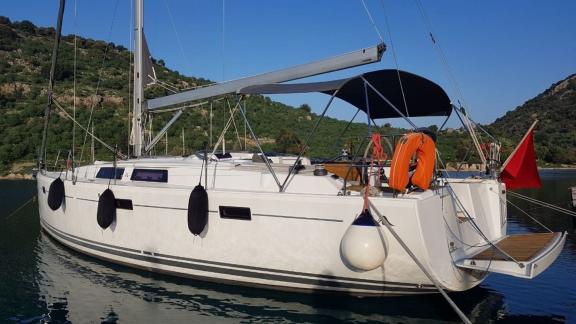 Beau Gosse sailing yacht anchored in a tranquil bay surrounded by greenery, offering a peaceful scenery.