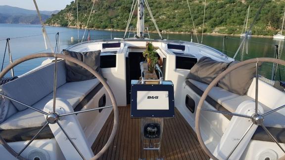 The helm station of the Beau Gosse sailing yacht features a seating area with comfortable cushions.