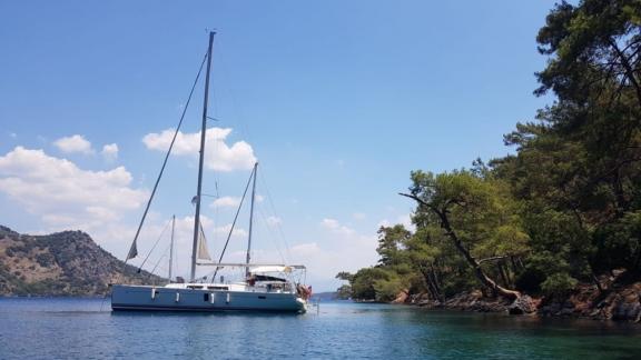 The sailing yacht Baxter is anchored in a peaceful cove surrounded by nature.