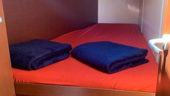 The double cabin of the sailing yacht Baxter is furnished with red sheets and blue blankets.