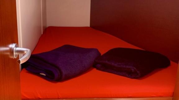 The double cabin of the sailing yacht Baxter is furnished with red sheets and purple blankets.