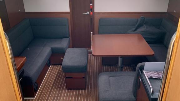 The interior of Baxter sailing yacht features a cozy seating area and a dining space with a wooden table.