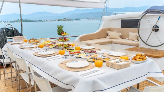 In Fethiye gulet charter option Happy Days aft deck with prepared breakfast table and seating area visible.